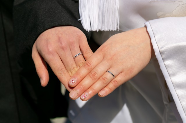 結婚指輪をした手を重ねる和装の新郎新婦の手