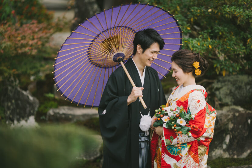 番傘をさして向き合う和装の新郎新婦