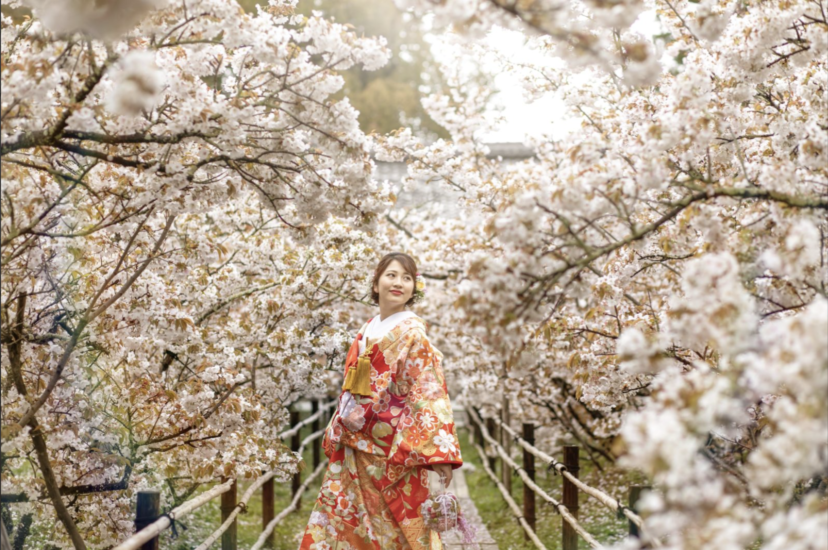 桜を背景に立つ和装の新婦