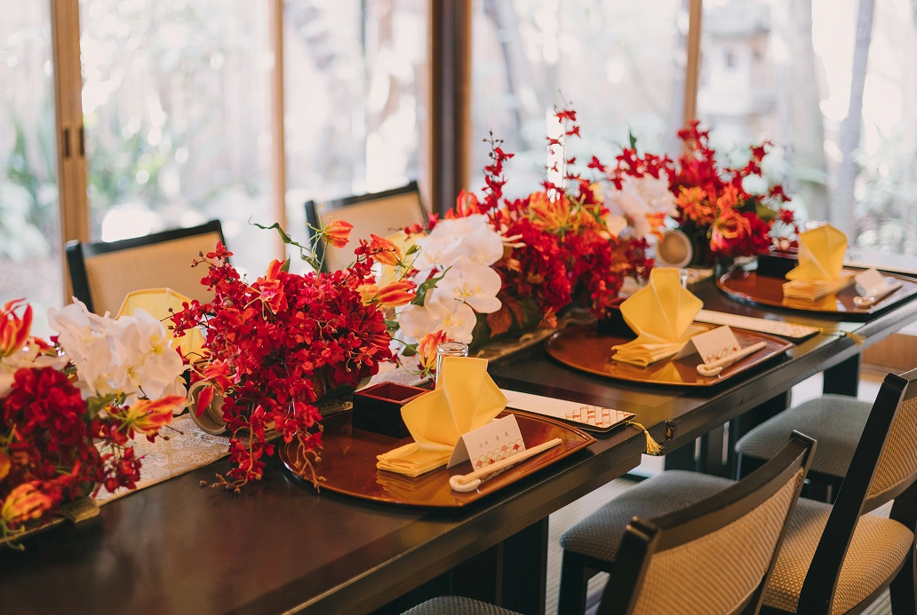 会食会場に並ぶ席札と赤白の装花
