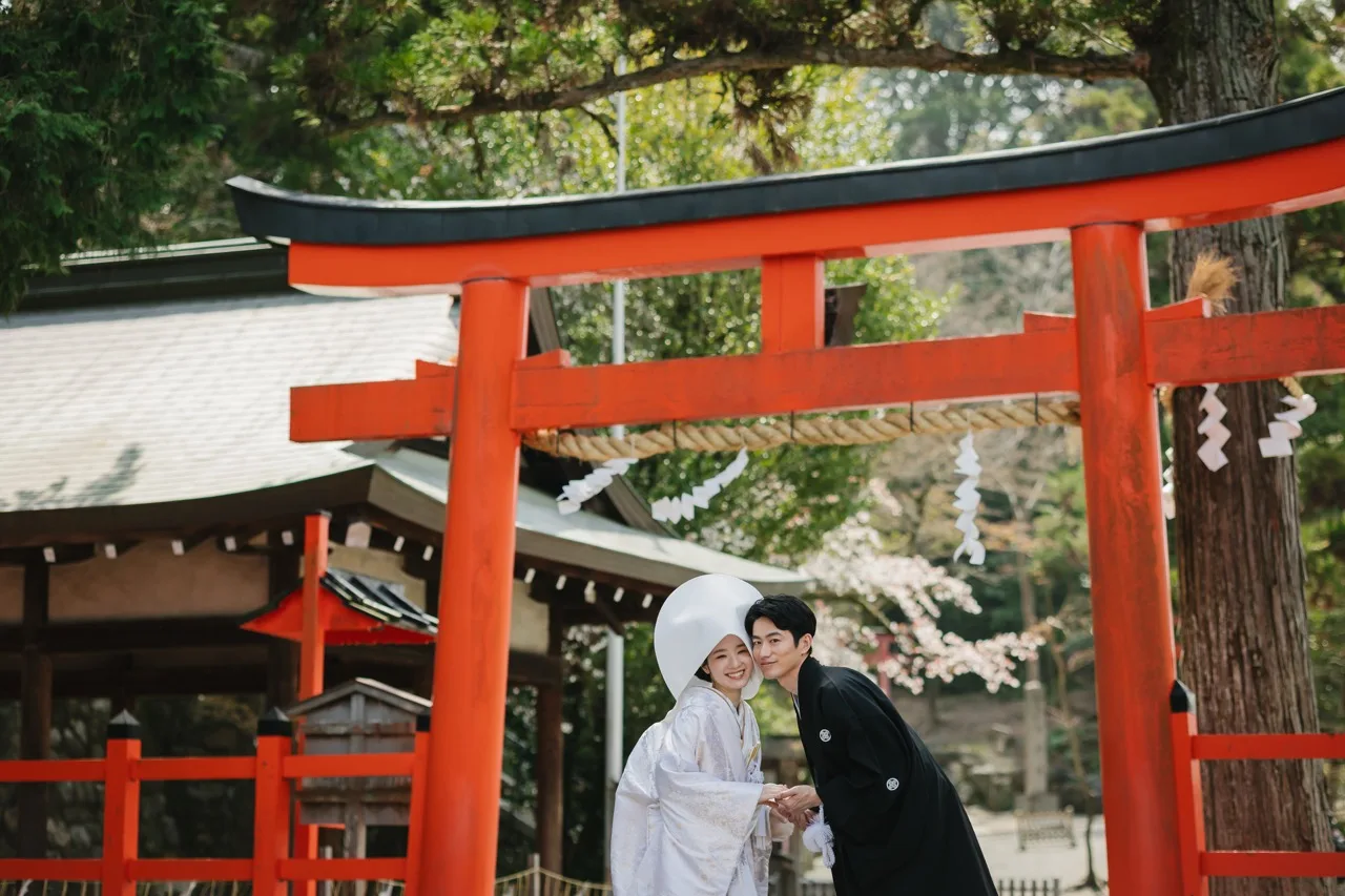 冬の澄んだ光のなか鳥居をくぐる新郎新婦